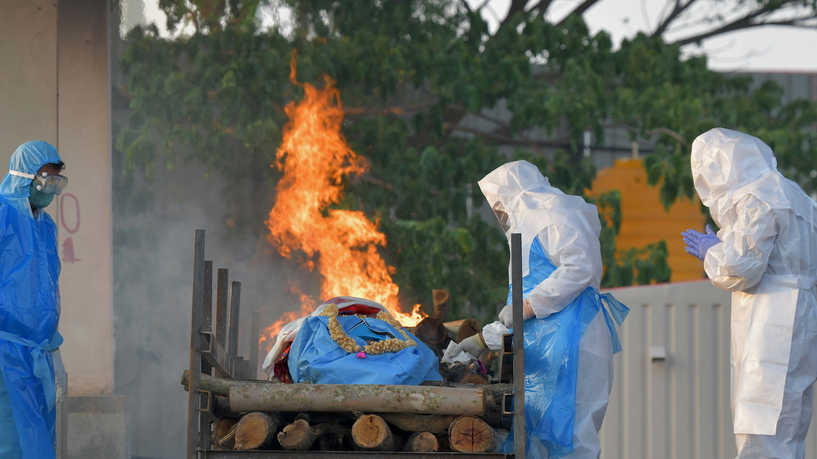 Family members and relatives wearing protective gear perform final rites of a victim who died of the Covid-19 coronavirus at an open crematorium in Bangalore on April 26, 2021. (Photo by Manjunath Kiran / AFP)