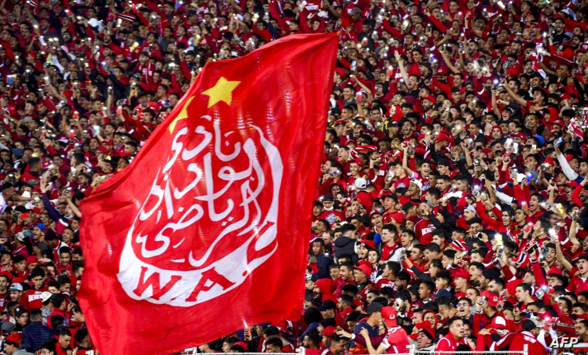 Supporters hold a giant Wydad's flag as they attend the CAF Champions league's match between Wydad Casablanca and Zamalek at the Mohammed V Stadium, in Casablanca, on February 26, 2022, after the reopening of the football fields in Morocco. (Photo by AFP)